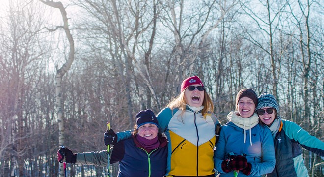 Friends huddled together in front of cliffs covered in snow and icicles