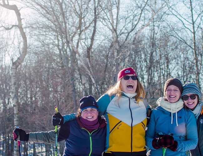 Friends huddled together in front of cliffs covered in snow and icicles