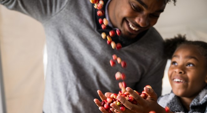 little girl smiling and holding a handful of cranberries