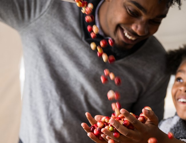 little girl smiling and holding a handful of cranberries