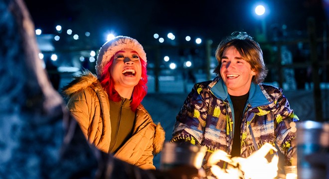 Friends laughing around a fire, outside at night