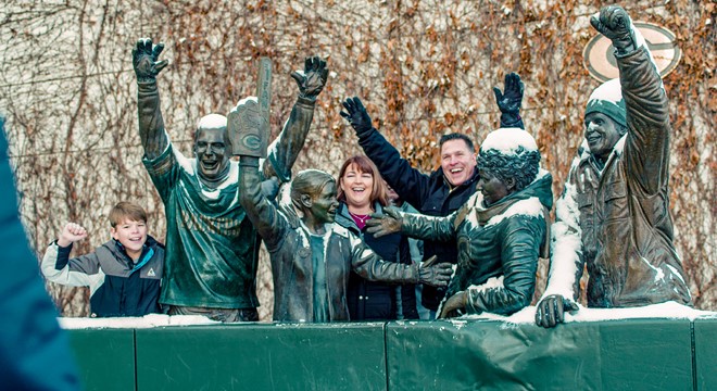 family posing around packers fan statues