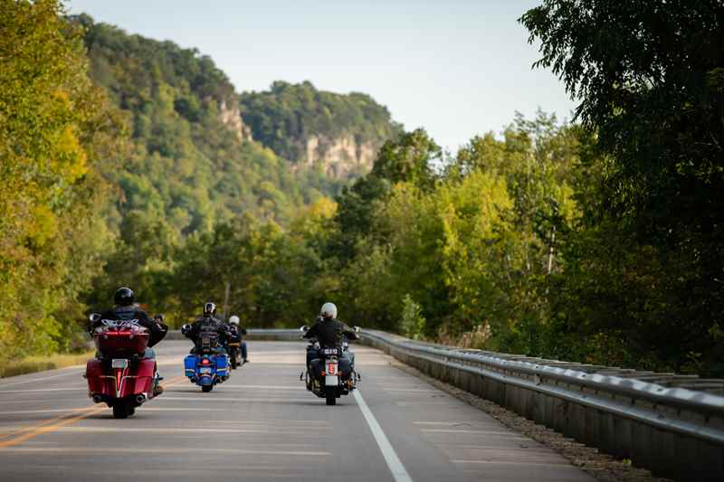 Group of motorcyclists riding on Great River Road with beautiful green trees in the background