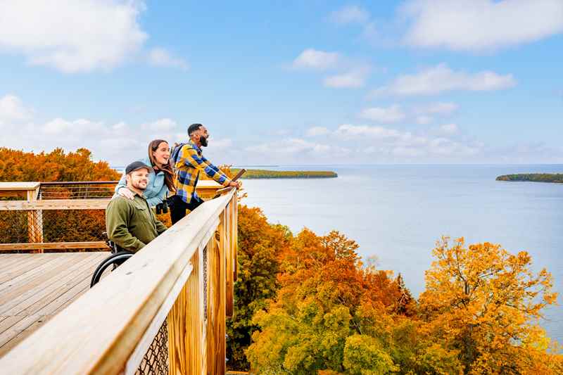 Friends group with a person in a wheelchair on an overlook, viewing Lake Michigan and beautiful trees of fall colors