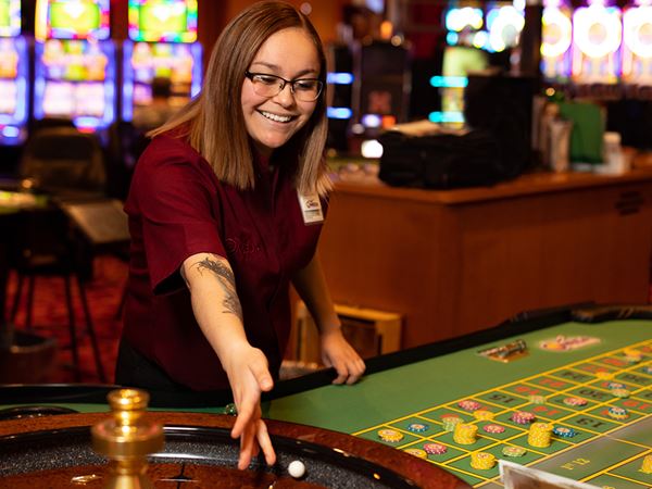 A roulette dealer spinning the wheel